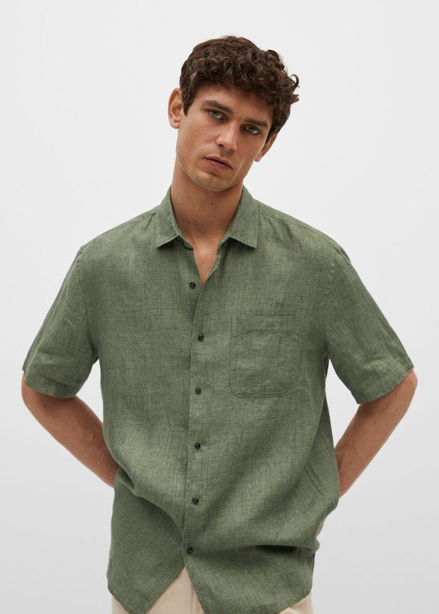 Man wearing a green linen shirt and beige pants on a white background